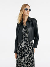 A lady wears a black leather jacket to a rock concert.